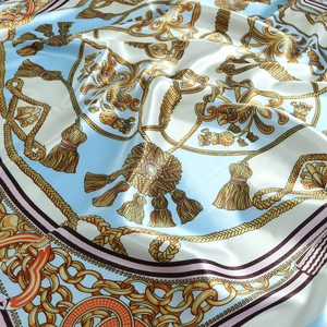 Detail of satin square scarf featuring baroque gold chain and tassel patterns on blue silk