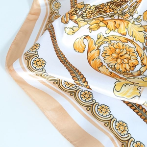 Detailed view of white and champagne gold satin scarf with baroque floral patterns