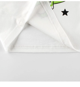 Detailed macro view of white cotton T-shirt hem with green dinosaur and star print