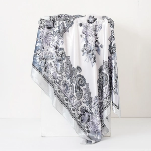 Detail of satin floral paisley scarf draped over minimalist stone props