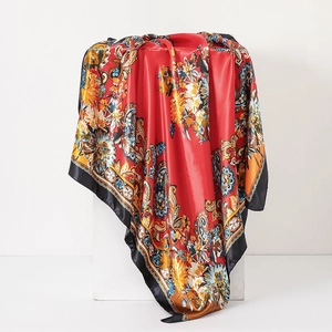 Close-up of red paisley silk scarf with colorful floral patterns on white display stand