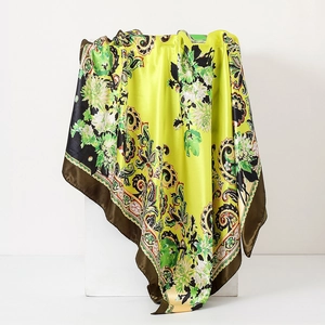 Detailed macro shot of vintage green paisley silk scarf draped on a white display block