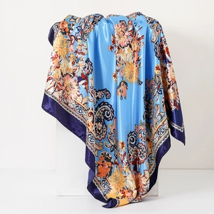 Close-up of royal blue silk scarf with golden paisley floral patterns and satin texture
