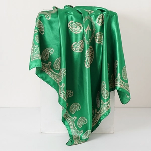Close-up of green paisley print silk scarf draped over a minimalist white geometry stand