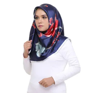 Detail of navy blue satin hijab featuring vivid red floral and berry patterns for women
