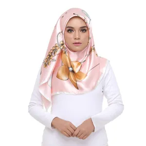Detailed view of pink satin silk scarf with yellow floral print worn as a chic hijab