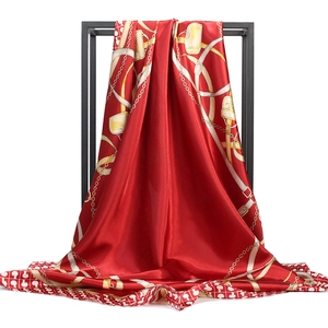 Detail of red satin scarf with golden chain print hanging on black metal rack