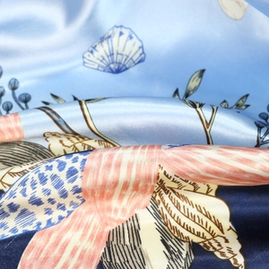 Close-up of printed satin silk scarf with seashell patterns and smooth texture