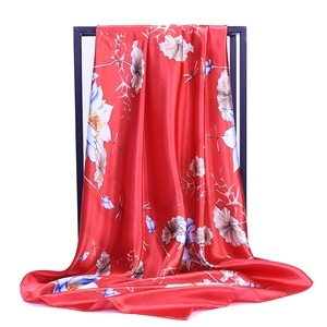Detail of red satin scarf showing elegant lotus prints and smooth glossy silk texture