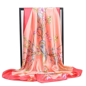 Close-up of floral satin scarf with coral and red patterns showing silky texture