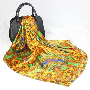 Golden paisley satin silk scarf 90cm square wrap displayed with luxury handbag