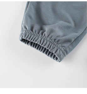 Détail du pantalon gris-bleu montrant les poignets élastiques et la texture tissée