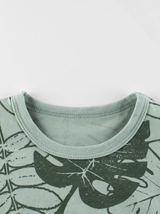 Close-up of kids' cotton t-shirt featuring green monstera leaf prints and ribbed crew neck
