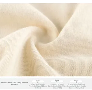 Vue macro du tissu en maille crème montrant une texture douce et des coutures de qualité
