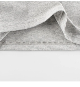 Dettaglio dell'orlo a doppio ago sul tessuto in maglia grigio melange della t-shirt bimbo