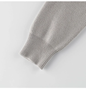Dettaglio macro di un maglione in maglia grigio chiaro con polsino a coste e trama liscia