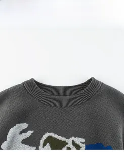 Detail of dark grey crew neck kids sweater showing ribbed collar and dinosaur pattern knit