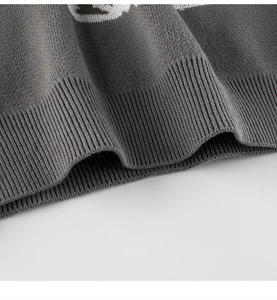 Detailed view of the ribbed hem and compact knit texture of a dark grey dinosaur sweater