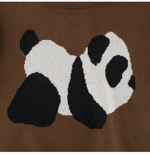 Detail of knit sweater showing cartoon panda pattern and ribbed crew neckline texture