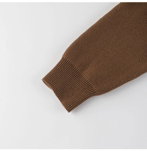 Close-up of dark brown knit sweater sleeve featuring ribbed cuffs and fine needle texture