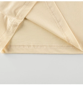 Vue macro détaillée de l'ourlet à double couture sur un t-shirt en coton beige enfant