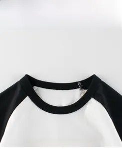 Detail view of cotton raglan t-shirt with black crew neck and 'the less you care' print