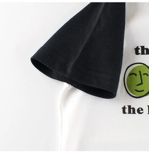 Close-up of raglan sleeve stitching and green smiley face print on kids cotton t-shirt