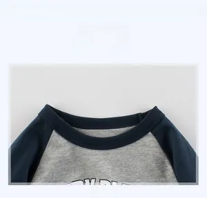 Détail d'un t-shirt bébé à manches raglan montrant l'encolure côtelée et le coton doux