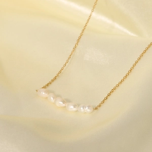 Elegant gold necklace with five baroque freshwater pearls on soft satin background