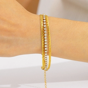 Three-layer gold-plated bracelet with curb chains and cubic zirconia on a wrist