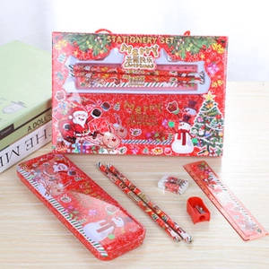 Red Christmas stationery set with pencil, ruler, eraser and tin box on wooden table