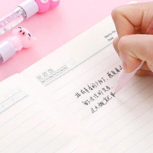 Stylo rose à paillettes avec figurine cochon écrivant sur un carnet