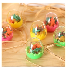 Detail of colorful dinosaur egg erasers in plastic shells on natural straw background