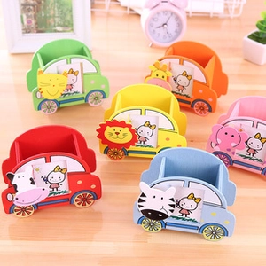 Close-up of animal-themed car pencil holders with photo frames on a wooden desk