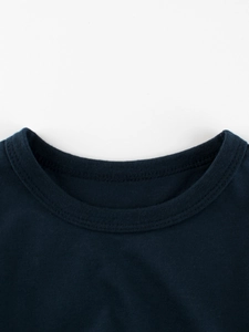 Gros plan du col rond côtelé de qualité sur un T-shirt en coton bleu marine pour garçon
