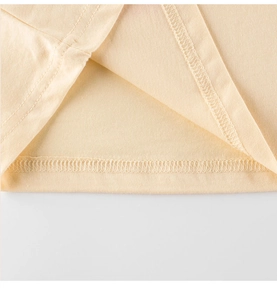 Gros plan détaillé des coutures et de l'ourlet de qualité sur un T-shirt enfant jaune