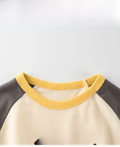 Detail of round neck with yellow ribbing and contrast raglan sleeves on cotton t-shirt