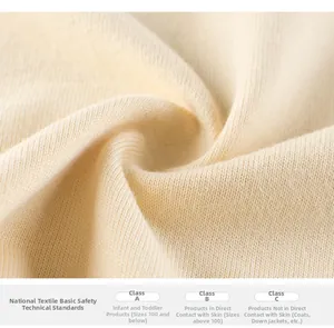 Close-up of soft beige knit fabric showing high-quality texture and safety certifications
