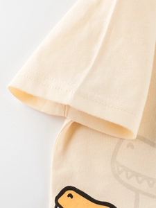 Close-up of boys beige cotton T-shirt with cartoon dinosaur print and double-stitched cuff