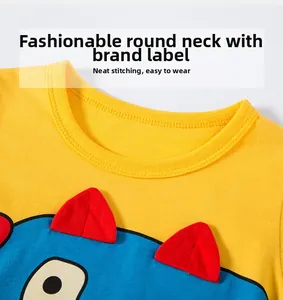 Détail du t-shirt jaune pour enfant avec col rond et décor de dinosaure 3D en feutrine