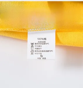 Détail de la couture de qualité et de l'étiquette 100% coton sur un T-shirt jaune pour enfant