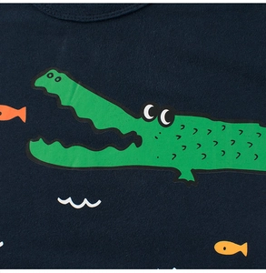 Close-up of a green cartoon crocodile print on a navy blue cotton t-shirt for boys
