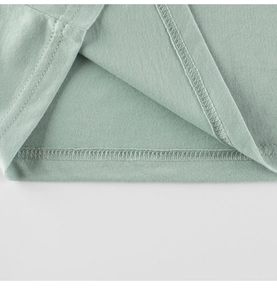 Gros plan détaillé de la double couture sur l'ourlet du t-shirt en coton vert clair pour enfant