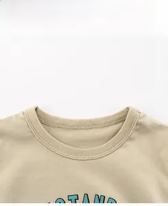 Close-up of ribbed neckline and cotton fabric detail on a beige boy's cartoon t-shirt