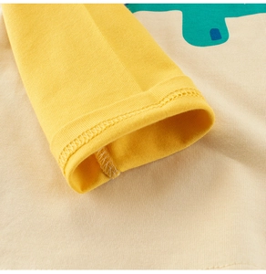 Dettaglio del polsino in cotone giallo e cuciture su una maglia a maniche lunghe con dinosauri