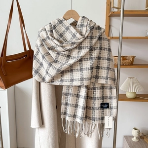 Classic black and white plaid cashmere-style scarf with elegant fringe tassels on a wooden hanger