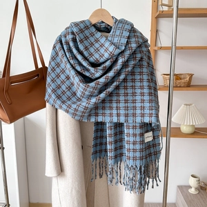 Detail of blue and brown plaid cashmere-like scarf with fringe on a wooden hanger