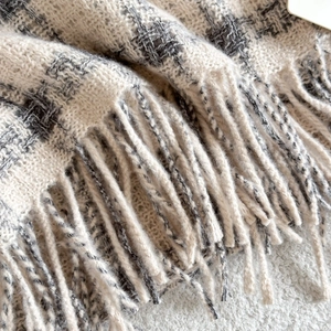 Macro detail of soft grey and white plaid scarf with delicate long fringe tassels