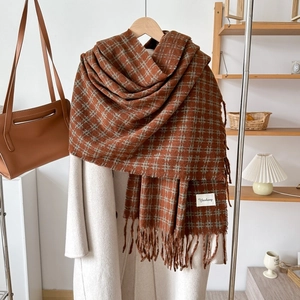 Detail of brown and grey plaid cashmere-like scarf with fringe and brand label