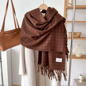 Detail of soft cashmere-feel scarf with plaid pattern and tassels on beige coat